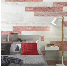 Schlafzimmerwand mit horizontalen Paneelen in verwitterter Holzoptik in Weiß und Rottönen, Bett mit Kissen, Regal und Stehlampe.