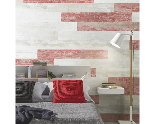 Schlafzimmerwand mit horizontalen Paneelen in verwitterter Holzoptik in Weiß und Rottönen, Bett mit Kissen, Regal und Stehlampe.
