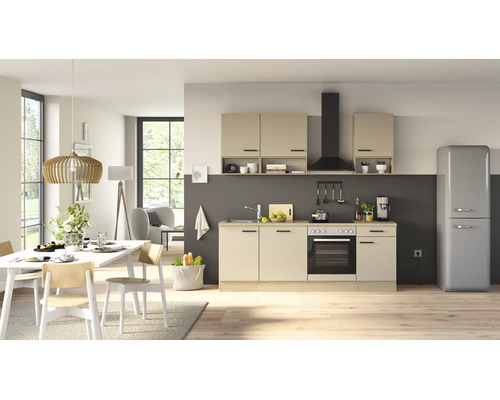 Cuisine équipée moderne avec façades claires, hotte aspirante noire, four et coin repas attenant dans une pièce lumineuse.