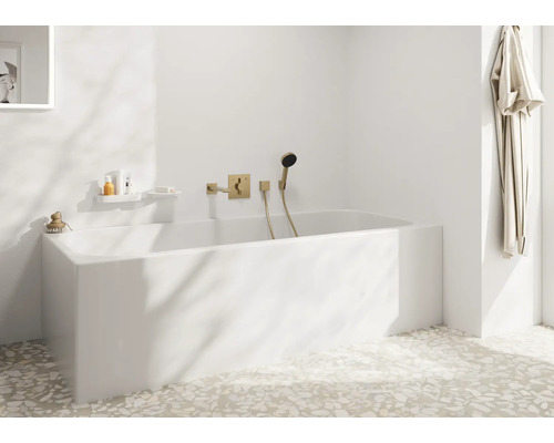Modernes Badezimmer mit weisser Einbauwanne und Unterputz Armatur in Metalloptik an der Wand, sowie Terrazzoboden und Bademantel am Haken.