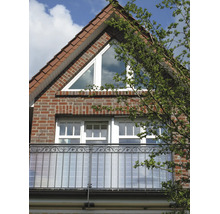 Balcon avec pare-vue en plaques alvéolaires et garde-corps en fer forgé sur une façade en brique avec fenêtre de toit.