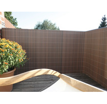 Brise-vue en plastique sur une terrasse en bois avec une plante en pot et un meuble de jardin au premier plan.