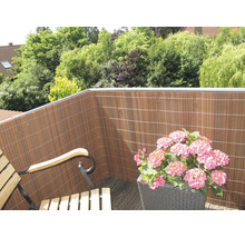 Balcon avec un écran de confidentialité en lattes de plastique et un bac à fleurs avec des hortensias