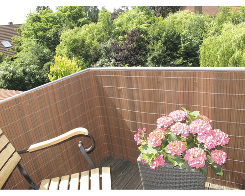 Balcon avec un écran de confidentialité en lattes de plastique et un bac à fleurs avec des hortensias
