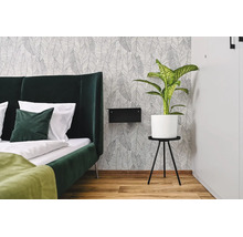 Chambre moderne avec papier peint intisse a motif de feuilles, lit rembourre, table de chevet et plante en pot.