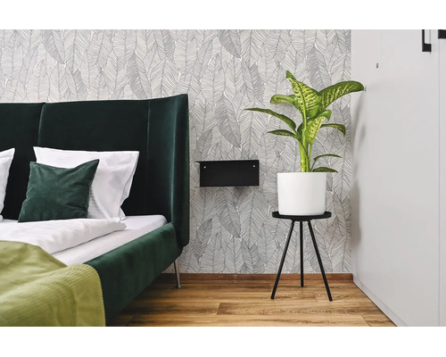 Chambre moderne avec papier peint intisse a motif de feuilles, lit rembourre, table de chevet et plante en pot.