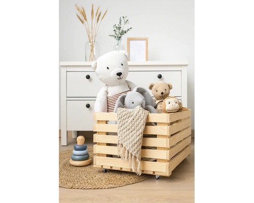 Caisse en bois sur roulettes remplie de peluches dans une chambre d'enfant organisée avec commode.