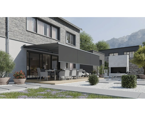 Moderne Terrassenmarkise mit ausfahrbarem Volant an einem Haus mit Backsteinfassade und Gartenbereich mit Sitzgruppe.