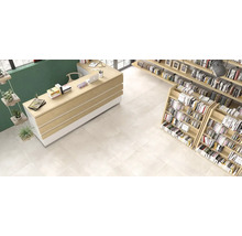 Innenraumansicht mit grossformatigen hellen Bodenfliesen in einem modern eingerichteten Raum mit Holztheke und Bücherregalen.
