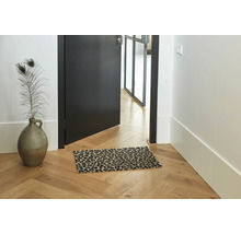 Fussmatte mit Leopardenmuster auf einem Parkettboden in einem hellen Flur mit einer Vase und einer offenen Tür.