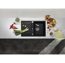 Évier encastrable moderne noir en composite dans une cuisine claire avec robinetterie, entouré de légumes frais et ustensiles de cuisine.