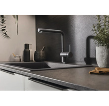 Moderne Küchenarmatur mit Ausziehbrause an einem dunklen Spülbecken in einer stilvollen Küche mit dunkler Rückwand.