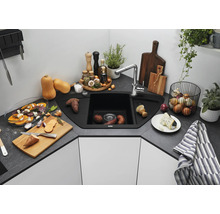 Évier d angle avec robinetterie dans une cuisine moderne avec plan de travail aspect pierre, entouré d ustensiles de cuisine et d aliments.