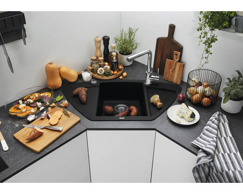 Eckspüle mit Armatur in einer modernen Küche mit Arbeitsplatte in Steinoptik, umgeben von Küchenutensilien und Lebensmitteln.