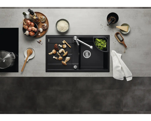 Évier encastrable moderne noir avec égouttoir et robinet de cuisine dans une cuisine organisée avec des ustensiles et des aliments frais.
