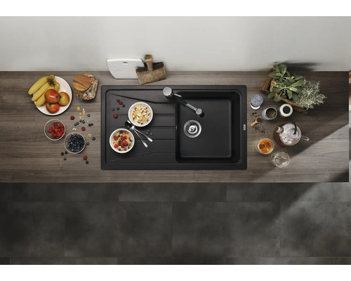 Vue de dessus d'un évier encastrable avec égouttoir dans une cuisine moderne avec plan de travail aspect bois et décoration.