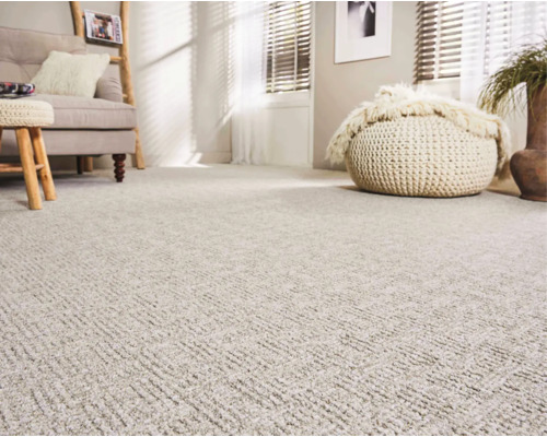 Wohnzimmer mit flächendeckendem Teppichboden in strukturierter Optik, helles Interieur mit Sofa und Sitzhocker für ein gemütliches Ambiente.
