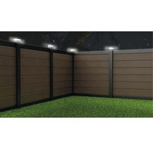 Clôture de jardin en bois composite avec éclairage LED intégré sur les poteaux, vue de nuit.
