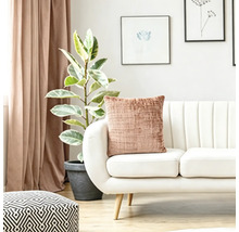 Coussin texturé sur un canapé blanc moderne dans un salon lumineux avec plante verte et rideaux