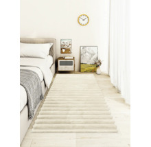 Ein weicher Hochflor Bettvorleger im modernen Schlafzimmer mit hellem Holzboden und strukturierten Streifen.