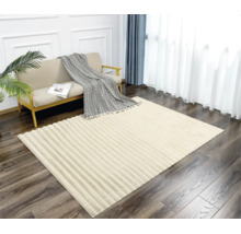 Ein rechteckiger Teppich mit strukturierter Streifenoptik liegt in einem hellen Wohnzimmer vor einem Sofa mit Decke.