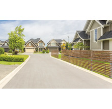 Eine ruhige Wohnstrasse mit Einfamilienhäusern und einem modernen Sichtschutzzaun aus Holz im Vorgartenbereich.