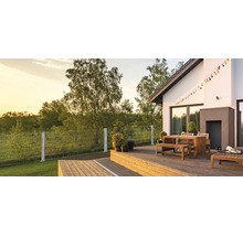 Moderne Holzterrasse mit Sitzgruppe aus Holz und einem Doppelstabmattenzaun im Garten bei Sonnenuntergang.