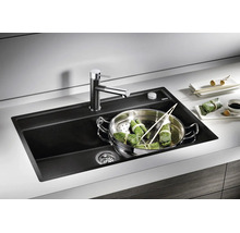 Moderne schwarze Einbauspüle aus Verbundwerkstoff mit Armatur in einer hellen Küchenarbeitsplatte und einem Dämpfeinsatz im Becken.