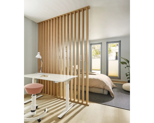 Moderne Raumtrennung durch vertikale Holzlamellen zwischen Arbeitsplatz mit Schreibtisch und Schlafbereich in einem hellen, offenen Wohnraum.