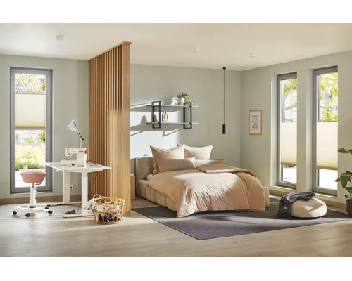 Ein modern eingerichtetes Schlafzimmer mit integriertem Arbeitsbereich, abgetrennt durch eine hölzerne Lamellenwand, mit Bett und Nähplatz.