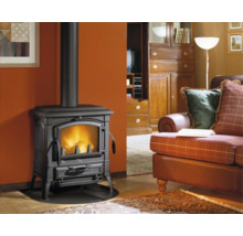 Poêle à bois en fonte au design rustique installé dans un salon avec un feu visible à travers la vitre et un conduit de fumée noir.