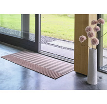 Un tapis de couloir rayé devant une porte-fenêtre, accompagné d un vase élancé avec des fleurs séchées dans un intérieur moderne.
