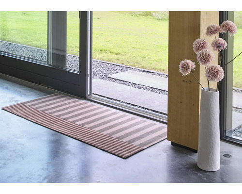Un tapis de couloir rayé devant une porte-fenêtre, accompagné d un vase élancé avec des fleurs séchées dans un intérieur moderne.