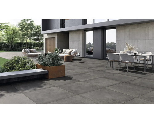 Dalle de terrasse moderne en grès cérame sur une vaste terrasse extérieure avec mobilier de jardin devant une maison moderne.
