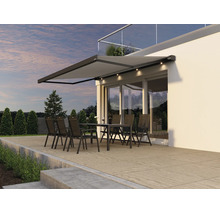 Store de terrasse moderne avec éclairage LED intégré au-dessus d'un salon de jardin sur une terrasse devant une façade de maison.