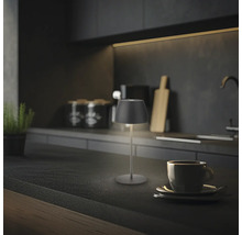 Moderne LED Tischleuchte auf einer Küchenarbeitsplatte neben einer Kaffeetasse in einer stilvollen dunklen Küche.