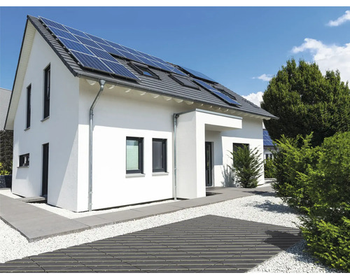 Modernes Einfamilienhaus mit Solaranlage auf dem Dach und einer gepflegten Aussenanlage mit gepflastertem Weg und Kiesbett.