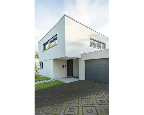 Modernes zweistöckiges Wohnhaus mit quadratischen Rasengittersteinen in der Einfahrt und angrenzender Garage.
