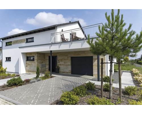 Modernes Wohnhaus mit Natursteinverkleidung am Erdgeschoss, Garage, Balkon mit Edelstahlgeländer und gepflasterter Zufahrt in einem Garten.
