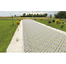 Gepflasterte Auffahrt mit quadratischen Rasengittersteinen in einem Gartenbereich mit Rasenfläche und Ziersträuchern.
