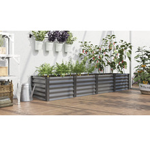 Jardinière surélevée rectangulaire en métal dans une serre avec diverses plantes comme des poivrons et des carottes sur un sol de terrasse.