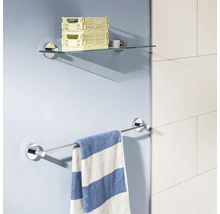 Étagère en verre et porte-serviettes en métal fixés au mur avec une serviette rayée suspendue dans une salle de bain moderne.