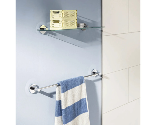 Étagère en verre et porte-serviettes en métal fixés au mur avec une serviette rayée suspendue dans une salle de bain moderne.