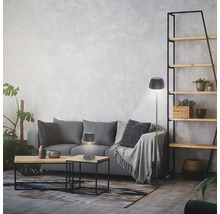 Séjour moderne avec une lampe de table et un lampadaire à abat-jour plissé devant un canapé gris contre un mur texturé.