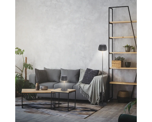 Séjour moderne avec une lampe de table et un lampadaire à abat-jour plissé devant un canapé gris contre un mur texturé.