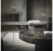 Vier LED Lampen mit plissiertem Schirm in den Größen Maxi, Nano, Mini und Classic in einem modern eingerichteten Wohnzimmer mit Kamin.