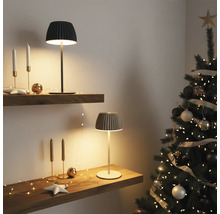 Zwei moderne Tischleuchten mit geripptem Schirm stehen auf Holzregalen in weihnachtlich dekoriertem Raum mit Weihnachtsbaum.
