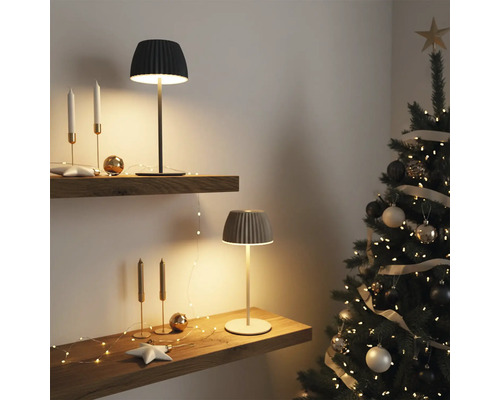 Zwei moderne Tischleuchten mit geripptem Schirm stehen auf Holzregalen in weihnachtlich dekoriertem Raum mit Weihnachtsbaum.