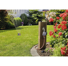 Arrosage de jardin avec programmateur d arrosage Gardena sur un poteau en bois, arroseur de pelouse et roses en fleurs.