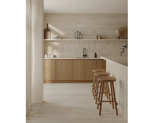 Cuisine moderne avec façades en bois, carrelages en pierre naturelle au mur et au sol, plan de travail et trois tabourets de bar.